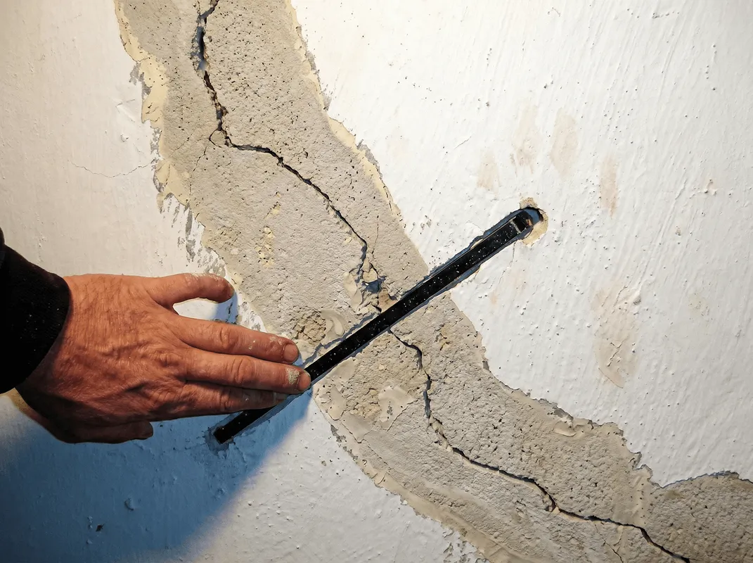 A wall with a large crack is being inspected by a professional in Bradenton, FL